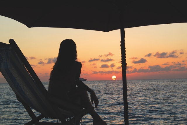 A woman sitting in a deck chair and watching the Caribbean sunset