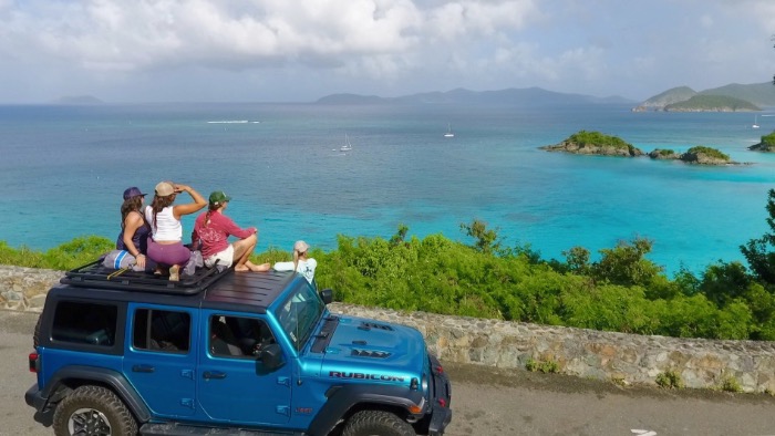 People sitting on roof of jeep Wrangler in US Virgin Islands.