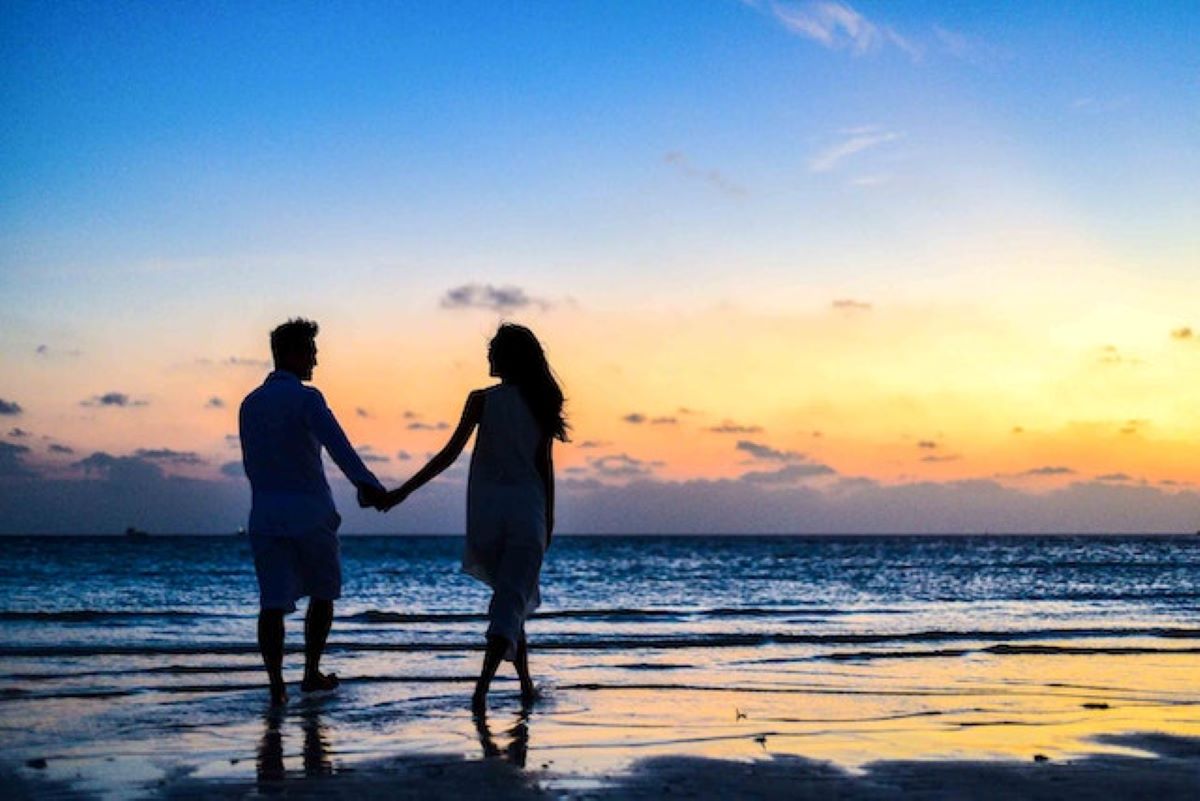 A couple is holding hands at the beach.