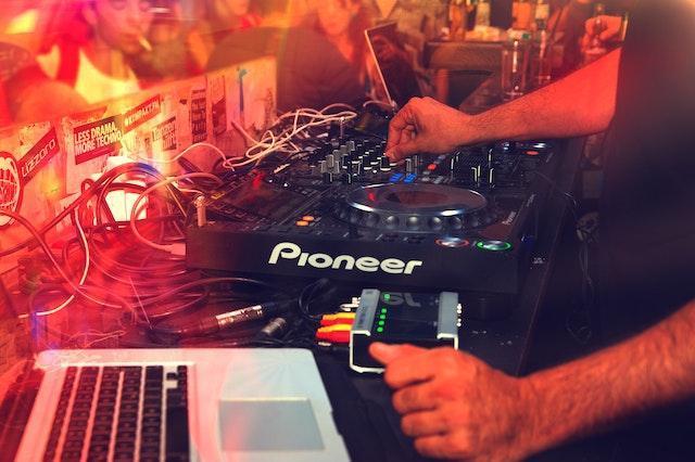 Man's hands on a turntable for a DJ and laptop