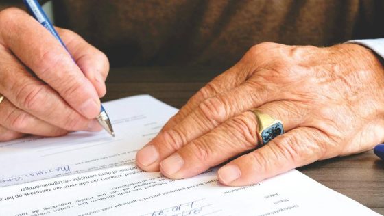 A man signing a document on a table 